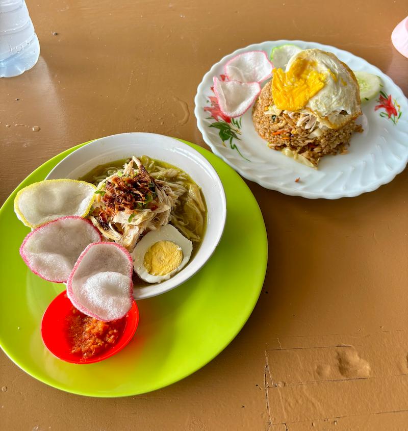 A delicious plate of Nasi Goreng with a fried egg on top, served alongside a bowl of Soto Ayam with turmeric-infused broth at a local warung in Canggu, Bali.