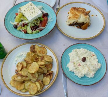 Traditional Greek meal at Ammos Restaurant in Armenistis, Sithonia – moussaka, crispy fried zucchini, tyrosalata cheese dip, and fresh Greek salad.